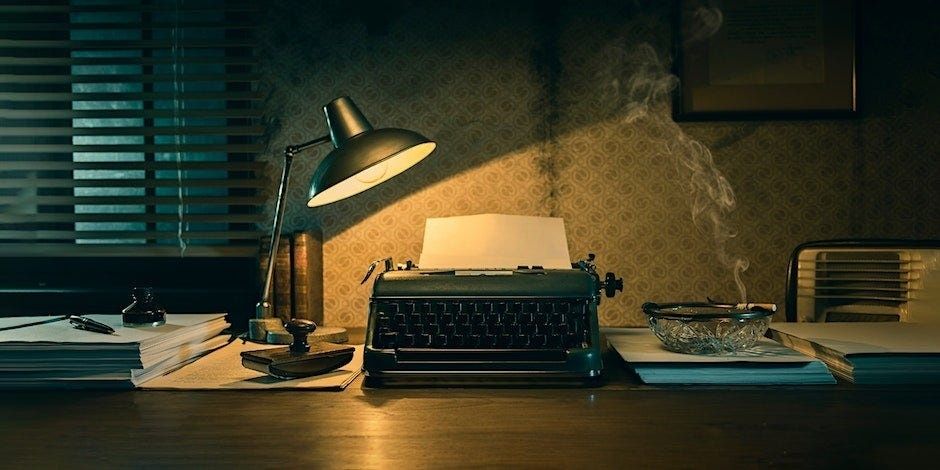 Machine à écrire éclairée, entourée de livres et de fumée