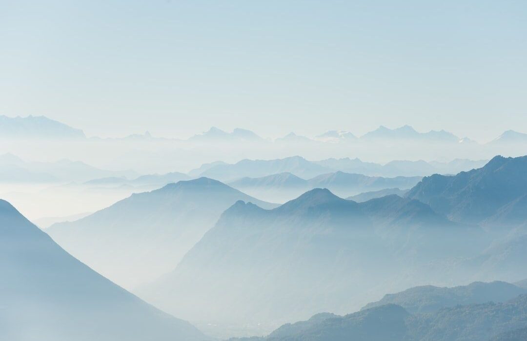 Paysage de montagnes bleutées émergeant d’une brume légère